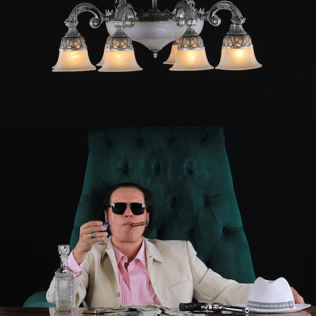 An old businessman in a white suit in the office at the table