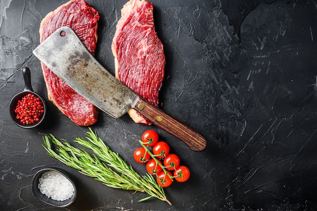 Old butcher cleave over raw picanha beef steaks with rosemary, peppercorns and salt