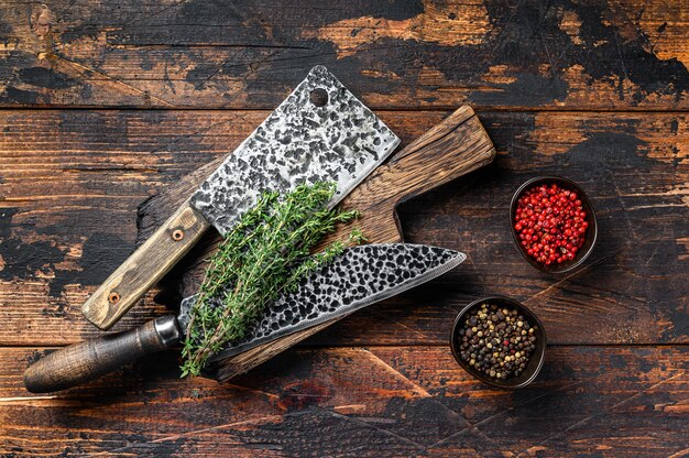 Old butcher meat cleaver and knife. Dark wooden background