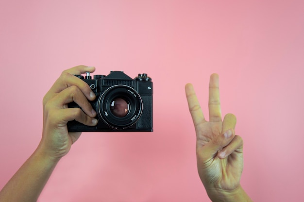 Old camera in female hands on a pink background