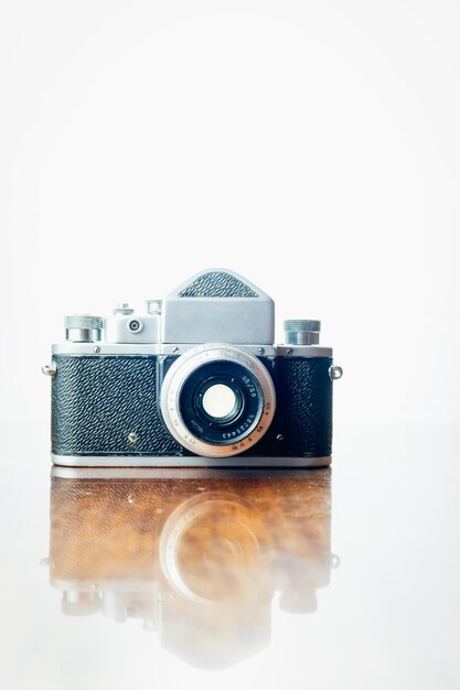 old camera with reflections on a wooden table high key