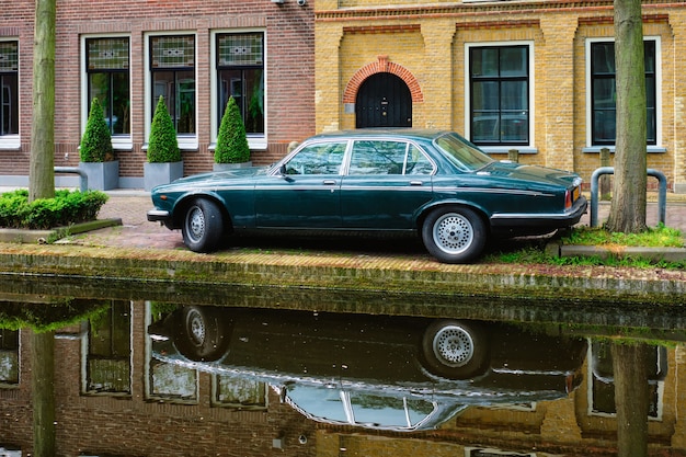 Old car on canal embankment in street of delft delft netherlands