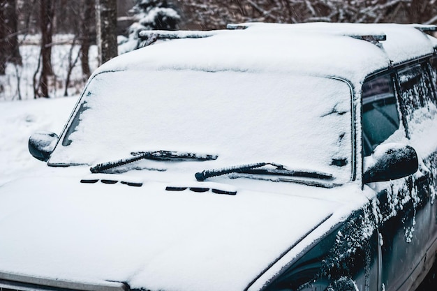 Старая машина засыпана снегом, едет в снежную погоду