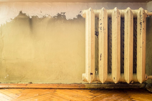 Old cast iron radiators with peeling paint on the wall