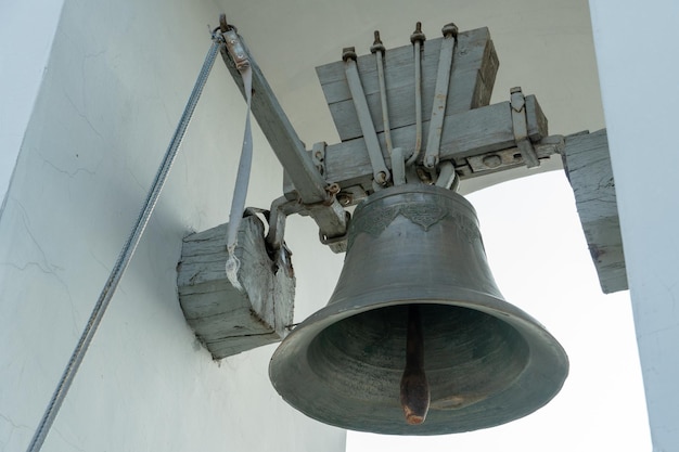 An old castiron bell hangs on a wooden frame at the top of the bell tower A historical building with a religious purpose