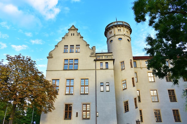 둥근 탑, 베이지색 벽돌 벽과 긴  ⁇ 은 창문이 있는 오래된 성 포즈난 폴란드