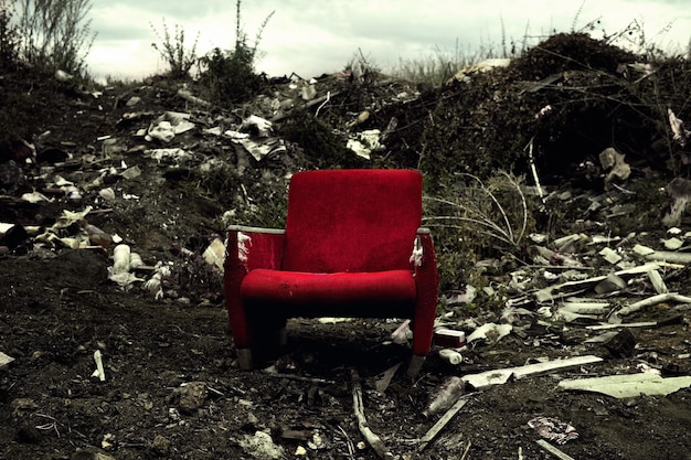 The old chair is in a landfill abandoned wasteland with waste\
and garbage