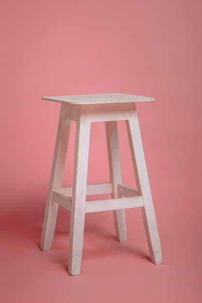 An old chair a wooden stool on a pink studio background Art object