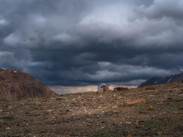 Old climbing house in the mountains under a stormy sky Empty mountaineering camp Authentic mountain dramatic landscape in the Altai Mountains