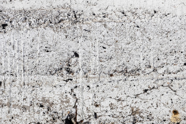 An old concrete wall with cracks covered with white paint. Grunge background. High quality photo