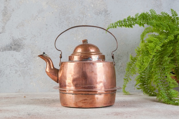 Old copper kettle on concrete background. Copy space for text, food photography props.