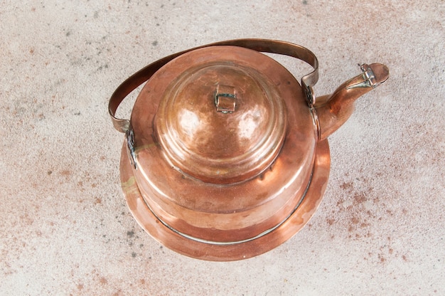 Old copper kettle on concrete background. Copy space for text, food photography props.