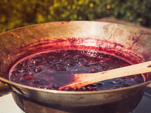 Old, copper pan, wooden spoon and plum jam