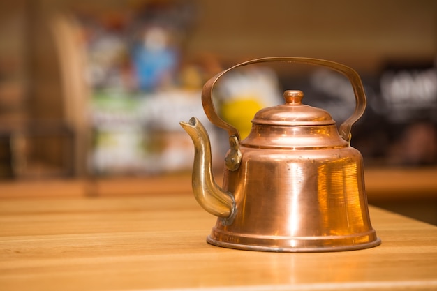 Old copper teapot on wooden table