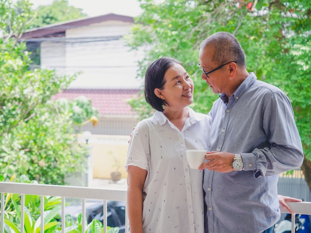 Old couple drinking coffee on the balcony