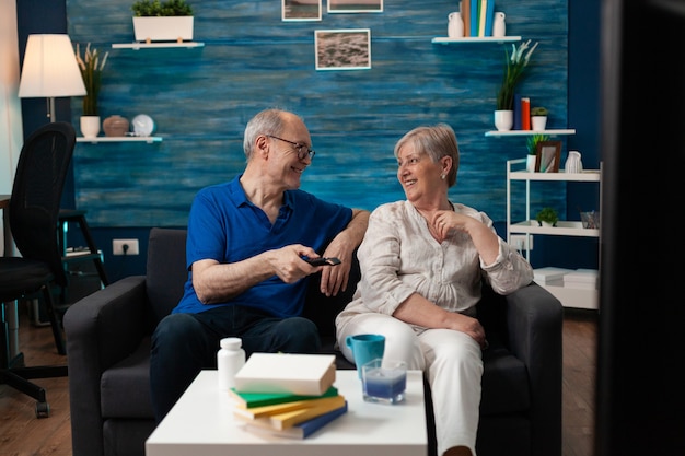 old couple enjoying retirement at home sitting on sofa