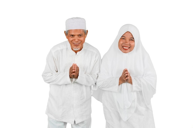 Old couple showing greeting gesture together during Eid Mubarak celebration isolated over white background