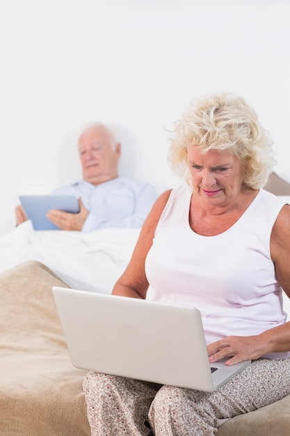 Old couple using a tablet and the laptop