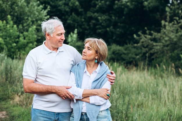 The old couple walks in nature, hold hands, cuddle