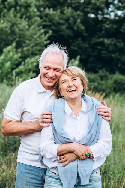 Photo the old couple walks in nature, hold hands, cuddle