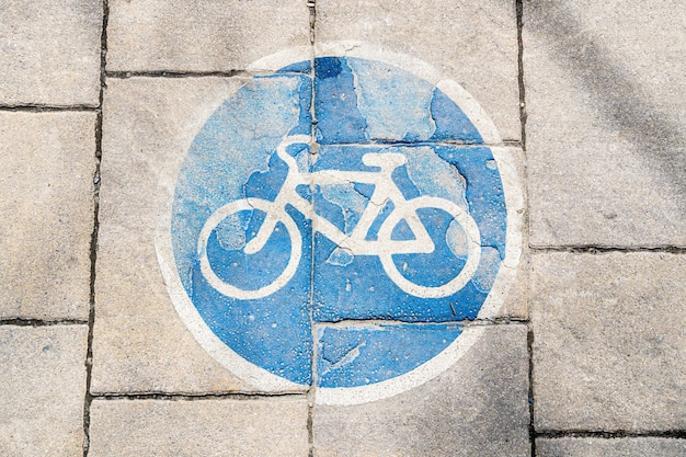 Old cracked bike line, path sign on road tiles