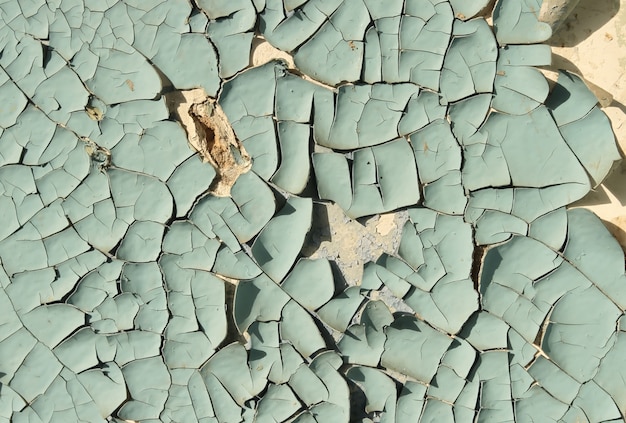 Old cracked paint blue on top of a white wall, side lighting sunlight