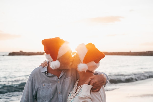 휴일에 크리스마스 모자를 쓰고 해변에서 함께 즐기고 즐거운 노년의 귀여운 커플
