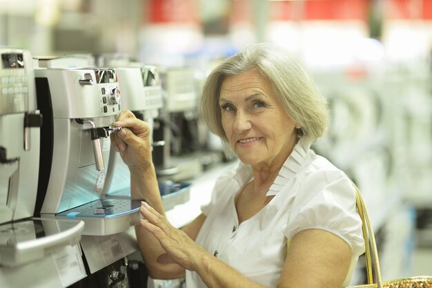 Old cute smiling lady choosing coffee machine