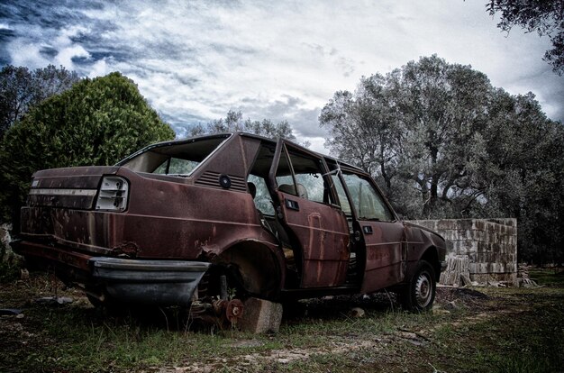 Photo old damaged car on field against sky