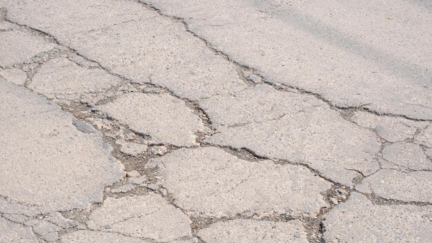 Foto vecchio fondo stradale in cemento danneggiato con consistenza rotta e fessurata sulla superficie