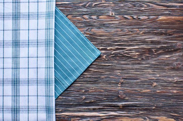 Old dark wooden background. Wooden table with green and white kitchen towels