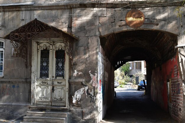 Old dilapidated house with a white door. House with an arch and a covered entrance.