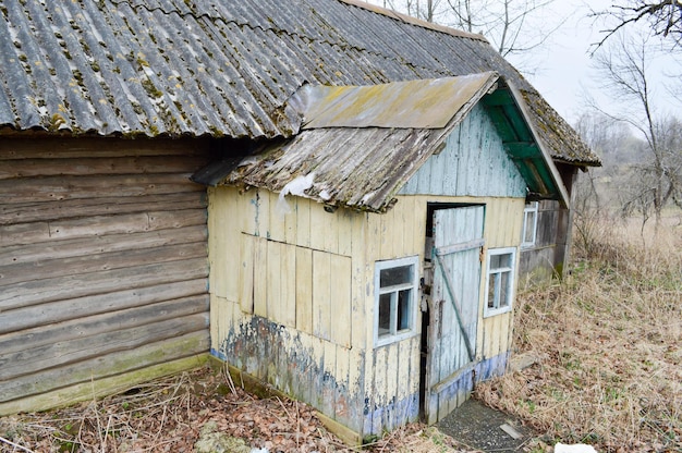 The old dilapidated porch the entrance to the wooden village house and the wall of dilapidated logs