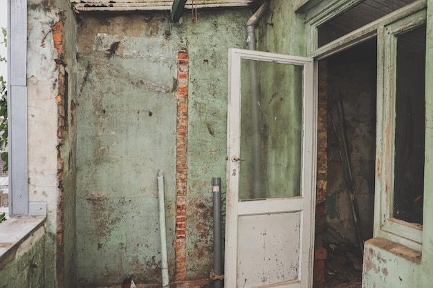 Old dirty doors with windows and a shabby green wall in an old abandoned house