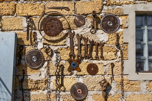 old dirty farm metal garden tools as shovels and rakes hanging on the wall on nails.