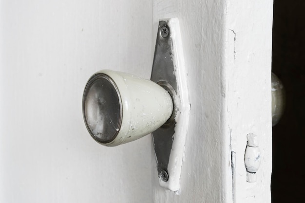 Old dirty painted white open door handle closeup