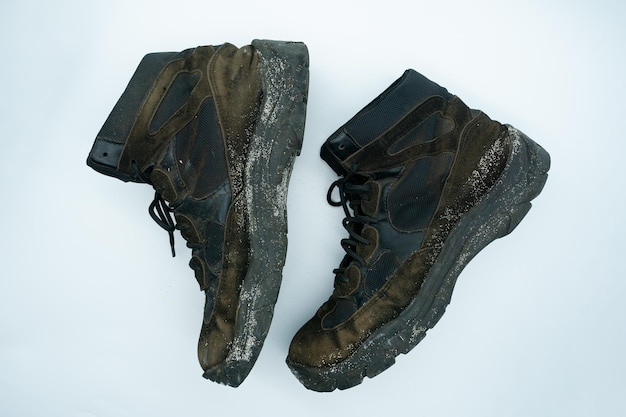 Old dirty sand and black work shoes with dirt on a white background