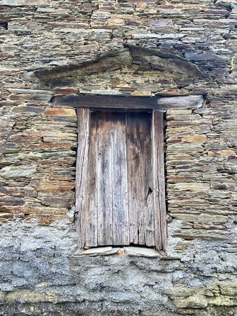Foto vecchia porta di tavole di legno in un antico muro di pietre senza gradini