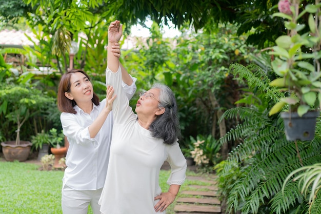 An old elderly Asian woman exercise in the backyard with her daughter Concept of happy retirement