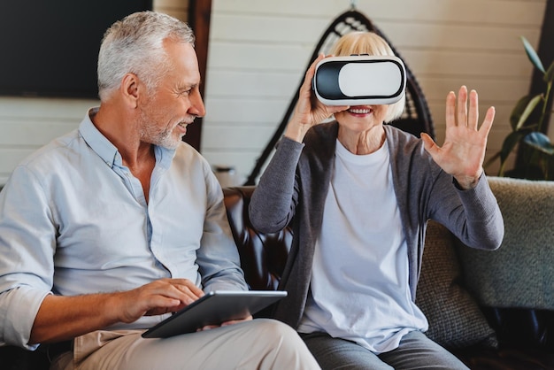 Old elderly retired woman using VR virtual reality headset in apartment