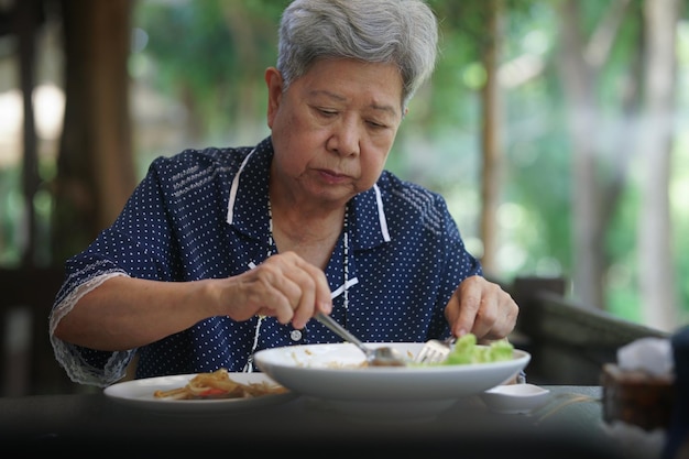 テラスで食べ物を食べる年配の高齢の年配の女性成熟した退職後のライフスタイル