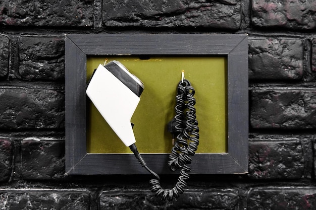 Old electric razor with curved cable in frame hangs on\
wall