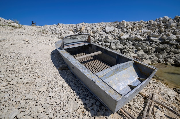 호수 또는 바다 해안 근처에 도킹 된 오래 된 빈 금속 낚시 모터 보트