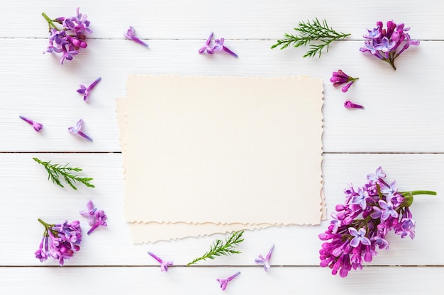 Vecchia foto vuota per l'interno e cornice di fiori lilla freschi su sfondo bianco di legno piatto