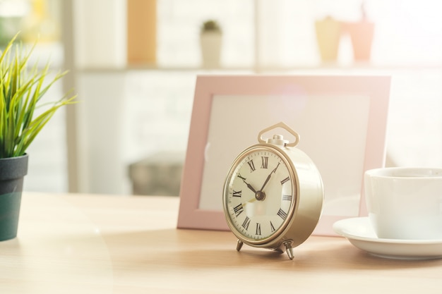 Old-fashioned alarm clock and house plant on wooden table