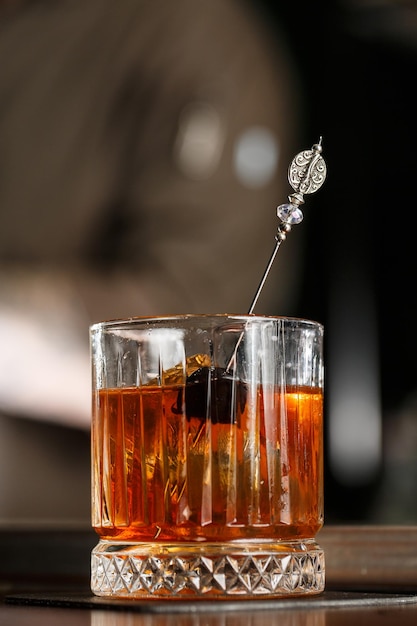 Old fashioned cocktail consisting of Bourbon Angostura Bitter sugar cubes a few drops of water ice cubes orange maraschino cherry