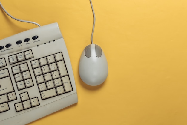 Old-fashioned retro keyboard and pc mouse on yellow. retro computer