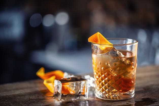 Old fashioned rum drink on ice with orange zest garnish.