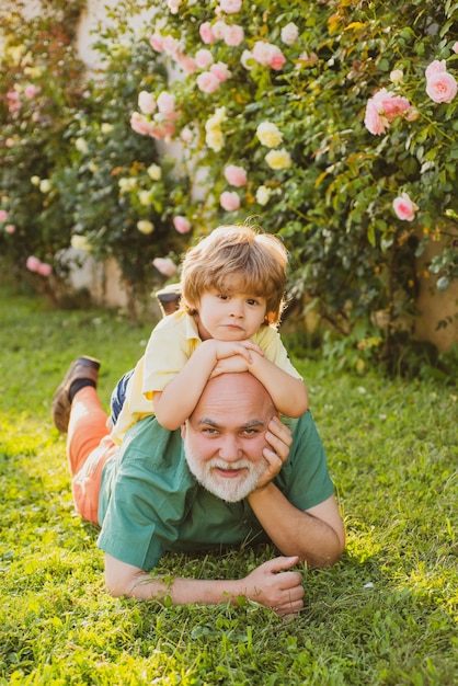 Old father play with son happy fathers day Father with Son having Fun in Park Family summer and active holidays Portrait of happy senior man father smiling and happy cute son