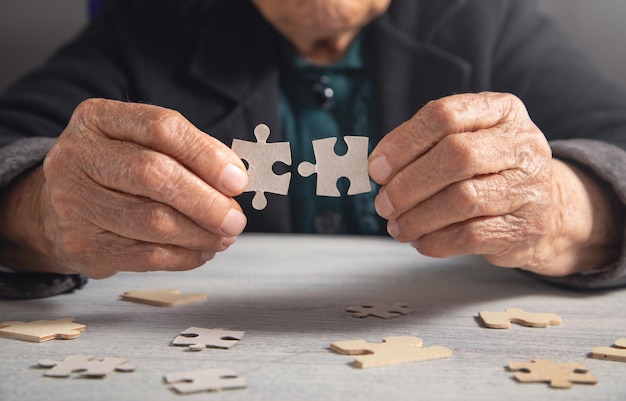 Foto mani di vecchie donne con un puzzle